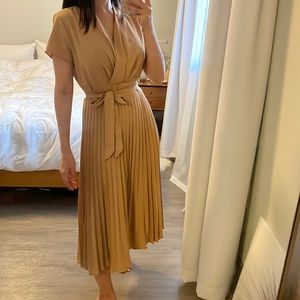 Beige dress with wrap top detail, pleated skirt, and tied waist